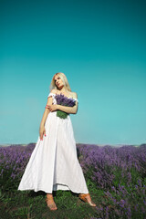 Fototapeta na wymiar Beautiful woman stands on lavender meadow. Summer time