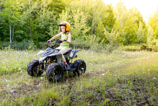Girl Having Fun Riding Fast Gas Powered Jr Kids ATV Quad Offroad Trail With Sunflare on Cottage Road