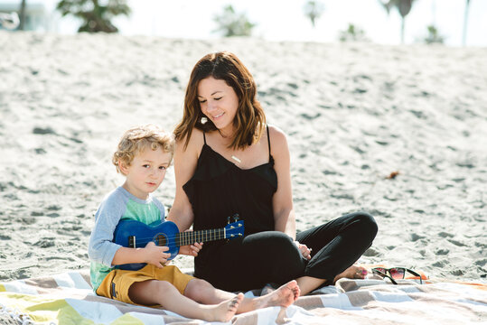 Young mom and son playing ukulele on the beach in San Diego.