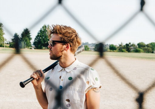Portrait of young man holding bat on baseball field