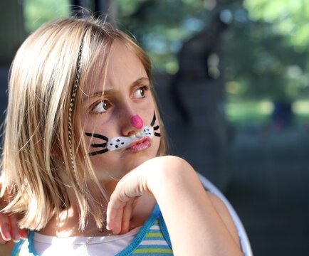 Little girl with a funny expression and cat whiskers painted on her face