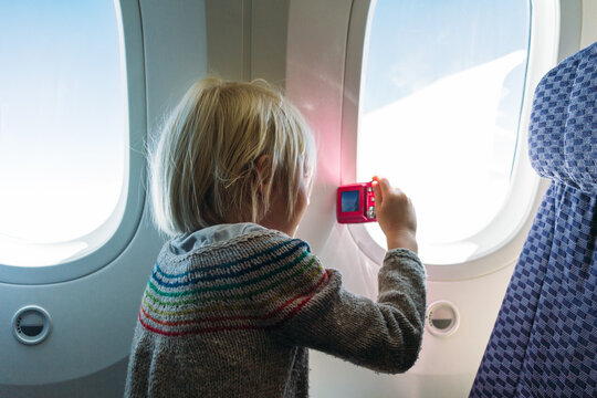 traveling girl taking pictures from inside airplane