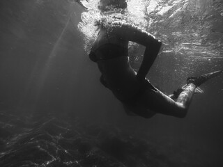 Moody underwater image of a woman snorkeling.