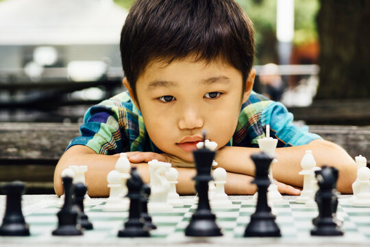Decision time - Asian boy, staring at a chess pieces