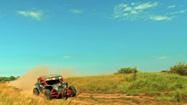 Buggy car going fast in cross country road. Fast rally auto is going with big clouds of dust. Speed riding of a racing off-road car in the rural road. Cinematic clip.