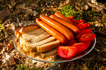 Sausages, bread and tomato - food to prepaire on a fire. Concept of outdoor cooking.