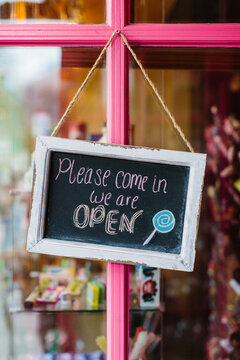 A pink door in front of a candy shop with a chalk board sign