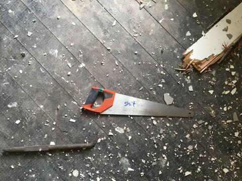 A saw on a wooden floor with shit written on it