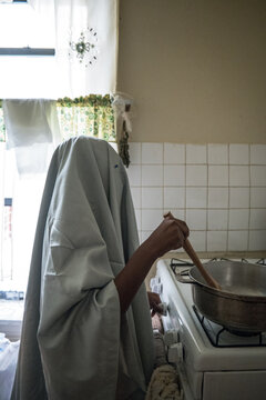 Young boy having fun pretending to cook as a ghost