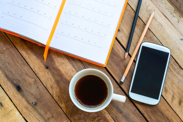 notebook planner ,mobile phone and hot coffee for business work of lifestyle arrangement flat lay style on background wooden