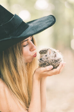 girl in a witch costume playing with a hedgehog