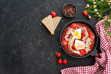 Christmas breakfast. Scrambled eggs with tomatoes, bacon and beans on a dark background with Christmas decor.