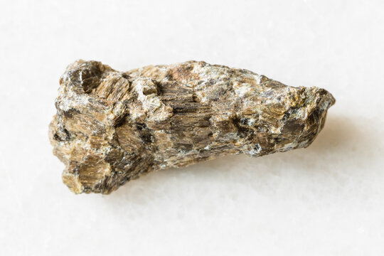 closeup of sample of natural mineral from geological collection - rough Bronzite (Enstatite) rock on white marble background from Rai-Iz massif, Polar Urals, Russia