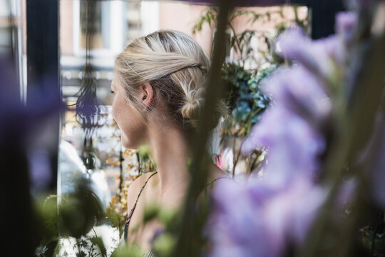 Blond woman looking away shot through purple flowers