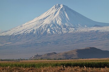 Ancient Armenian monastery Khor Virap against the background of the snow-capped peak of Ararat and fields
