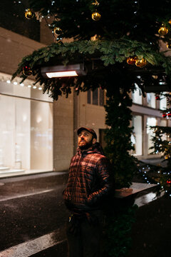 Man looking up at the decorations in the snowing city at Christmas time
