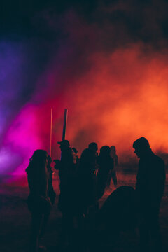 silhouettes of people in front of a colorful smoke