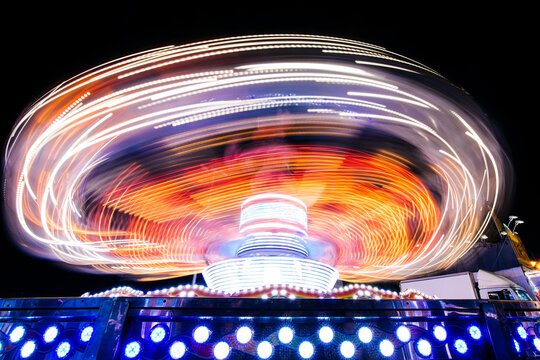 Spinning ride in a fair at night with colorful lights