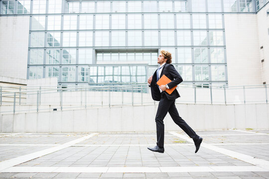 Young man in a suit running outside the office