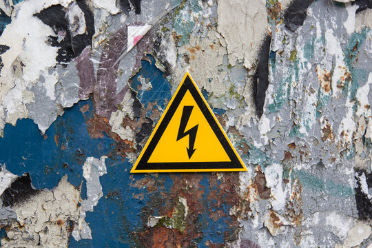 Electricity sign on a metal door covered with paint residue