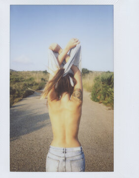 from behind: young woman taking off her clothes