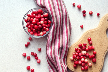 Fresh cranberries on the kitchen table in a glass Cup, on a cutting Board, Burgundy napkin, close-up, side view © MARYIA
