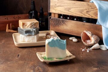 Natural handmade soap bar in ceramic soap dish with spa accessories on wooden table