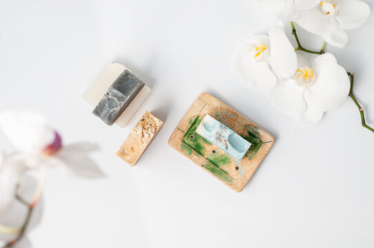 Natural Handmade Soap Bar In Ceramic Soap Dish With Orchid Flowers On White Table