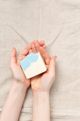 Woman holding natural handmade soap bar on linen fabric background