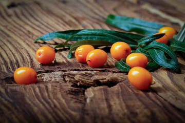 Fresh ripe berry Sea buckthorn with leaves isolated on wooden background with copy space for your text.