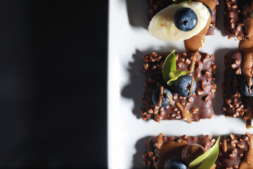 Chocolate dessert with nuts and fresh berries. Sweet snack for coffee biscuit in glaze and nut crumbs with fruit.