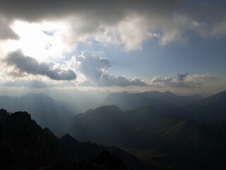 Berggipfel, Silhouette mit dunkler Wolkenstimmung und Sonnenstrahlen.