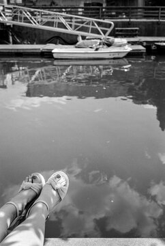A woman's feet dangle over harbor water on a summer day
