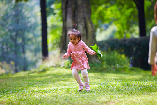 lovely little asian girl jumping in the sunny lawn