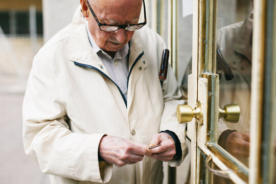 Elderly man opening the door of house.