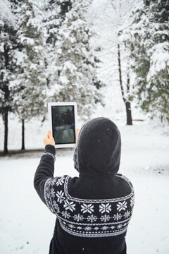 Woman taking a photo of snowy trees
