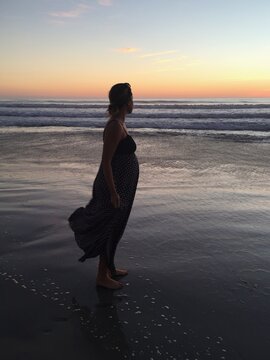 Pregnant Woman Standing Happily on Beach Thinking About New Beginnings.