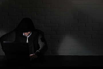 Hacker in black mask and hood at the table