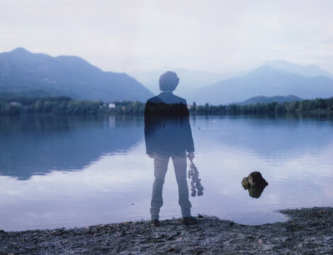 Double-exposure on Polaroid Film of a young man holding dried flowers by a lake