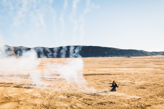 A man kneeling in the desert as he sets off fireworks