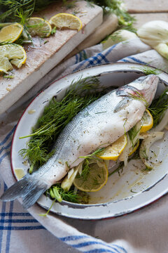 Fish prepared with lemons and aromatic herbs on an old tray to put in the oven