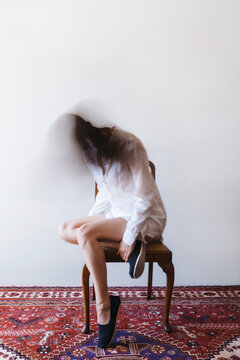 Unrecognisable woman sitting in chair with blurred head, intentional movement