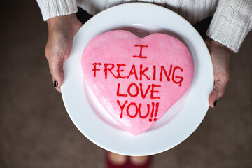 Woman holding a cake with the says ""I Freaking Love You!!""