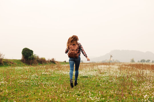 Back view of a 14 years old girl running in a field.