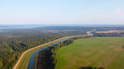 Fototapeta premium A view from the sky to a blue narrow flat river in the fields