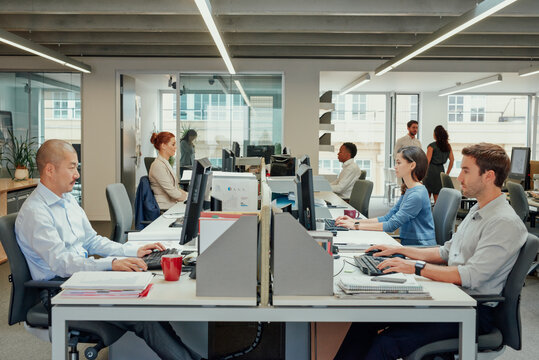 Rows of business people working at computers in stylish modern office