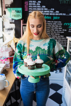 Young woman holding holiday cupcakes