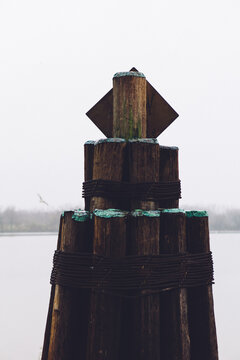 Fender pile at docks on a foggy river.