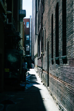 Narrow, dead end alley half lit by sunlight