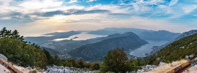 Stunning panorama of Montenegro, city of Kotor, Perast, Tivat and marvelous Kotor bay. View from highest point on mountain road. Beautiful mountains of Montenegro above the sky with clouds at sunset.